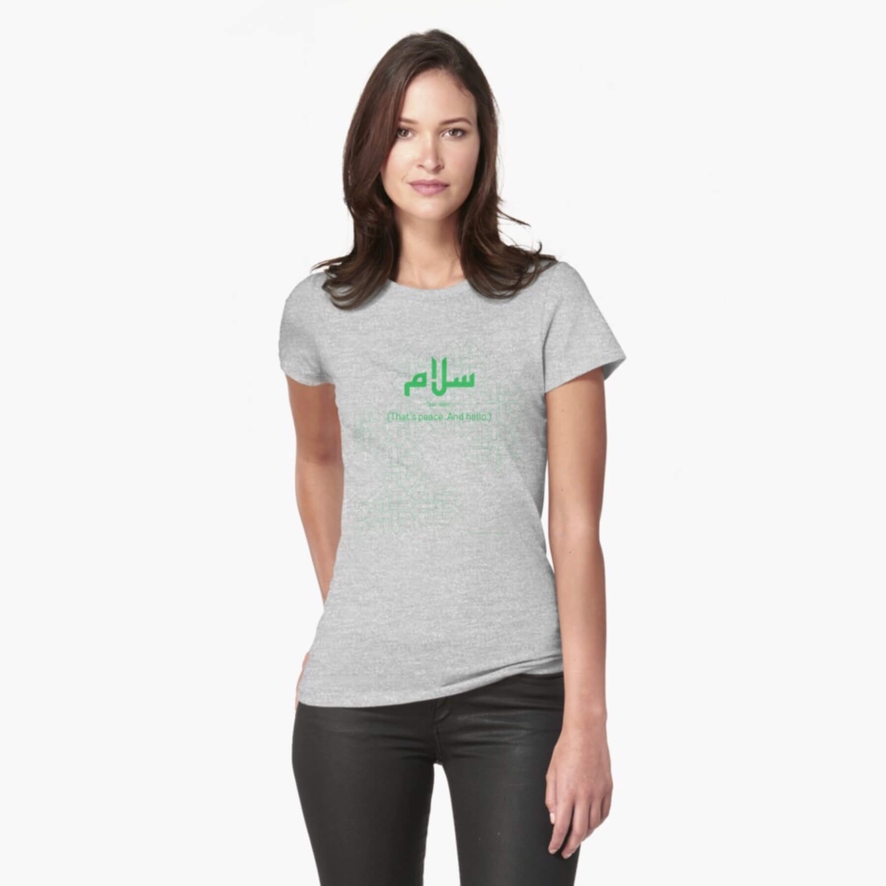 A white female model with hazel eyes and mid-brown shoulder length hair wears the Haluna Happy Names exclusive 'Salaam—Arabic Key Words' design purple fitted t-shirt and a pair of tight black jeans. The word 'salaam' is written in green in Arabic kufic-style font against a complementary green patterned background. The image cuts off mid-thigh. 