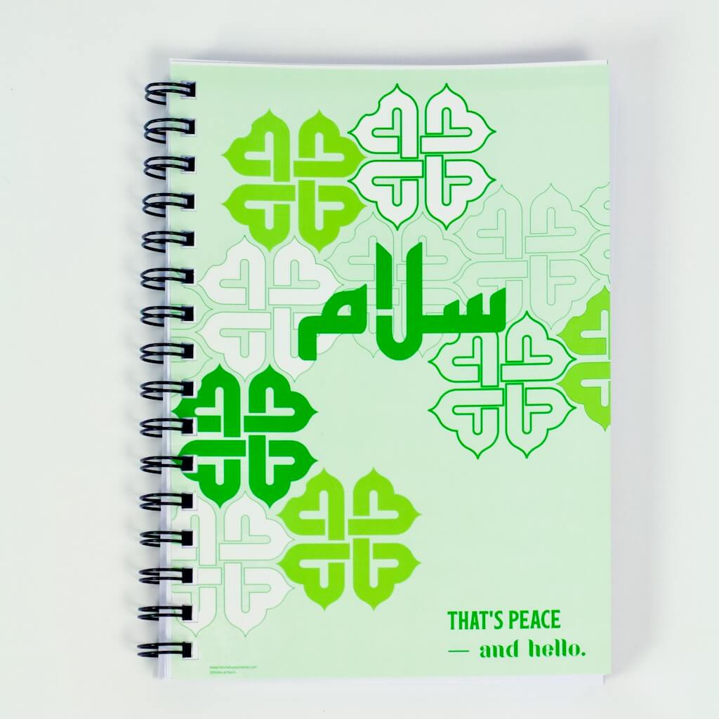 &#39;Salaam&#39; in Arabic Kufic font  and &#39;That&#39;s peace  — and hello.&#39; written against a partial repeating interlocking 4-part interwoven graphical element  is the design on the pale green cover of this Haluna Happy Names A5 spiral notebook with 200 silky smooth pages 
